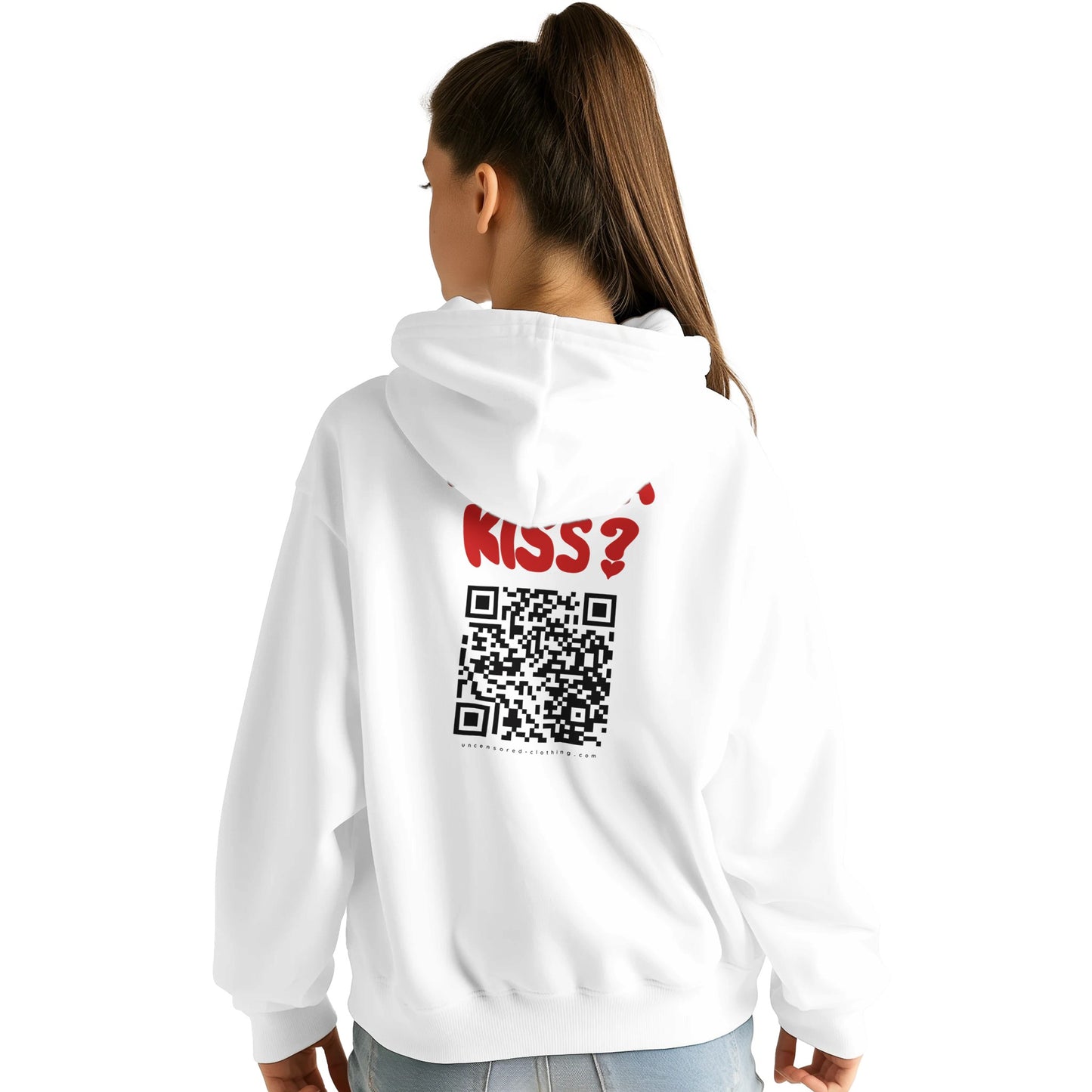 A young woman wearing a white hoodie, showing the back design. The hoodie features bold red text saying "WANNA KISS?" above a large black QR code. Below the QR code, the website "uncensored-clothing.com" is printed. The fit is slightly oversized, and the model is styled casually with jeans.